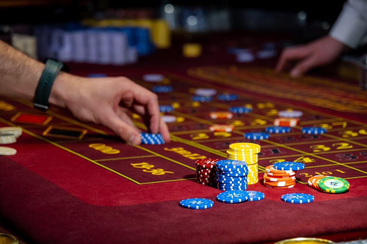 Man playing at the roulette table. A close-up vibrant image of multicolored casino table with roulette in motion, with casino chips. the hand of croupier. Man playing at the roulette table. A close-up vibrant image of multicolored casino table with roulette in motion, with casino chips. the hand of croupier.