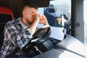 Exhausted,Truck,Driver,Rubbing,His,Eyes,In,The,Cab,After