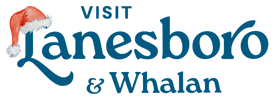 Holiday-themed ‘Visit Lanesboro & Whalan’ logo featuring the word ‘Lanesboro’ in blue script with a red-and-white Santa hat placed over the letter L.