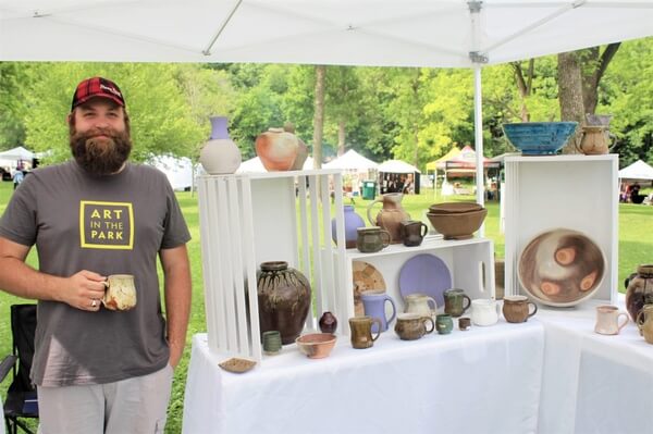 Photo courtesy of Lanesboro Arts A man standing by his art booth during the annual Art in the Park festival
