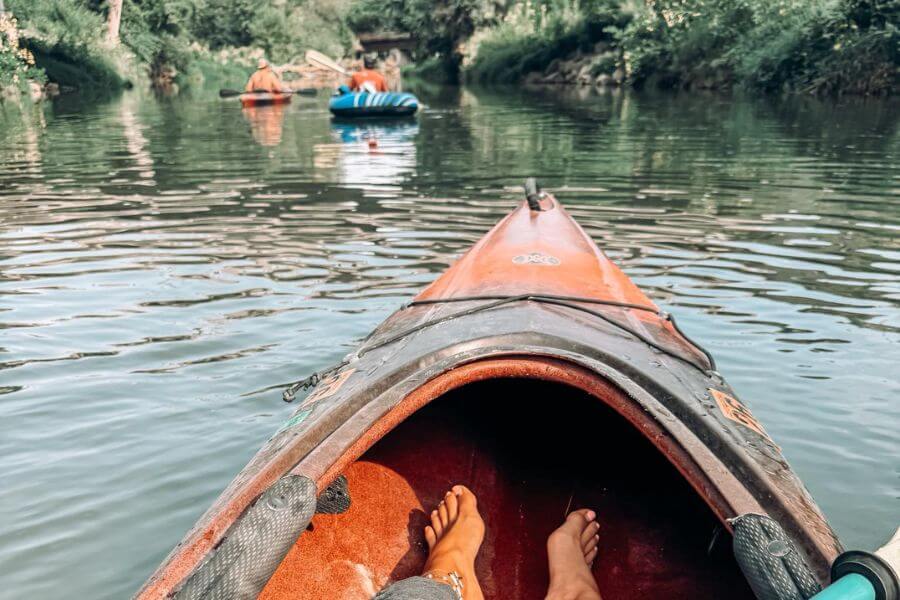View from inside a kayak floating on the Root River in Lanesboro, with other paddlers and tubers enjoying the calm water on a summer day.