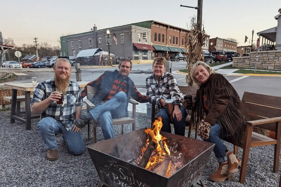 Two couples having beer around a bonfire at Sylvan Brewing in Lanesboro, MN