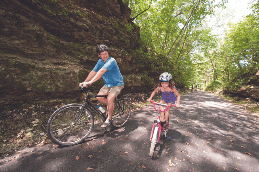 Father and daughter riding bikes on the Root River State Bike Trail near Lanesboro, MN
