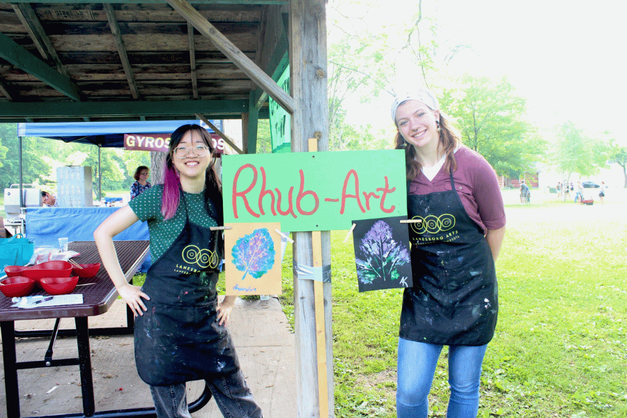 Two women standing next to a Rhub-Art sign at the Rhubarb Festival in Lanesboro, MN