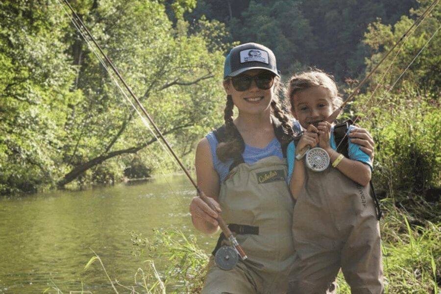 A mom and daughter holding fishing rods by the Root River near Lanesboro, MN