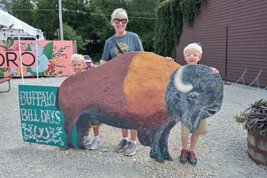 A mom and children behind a wooden buffalo