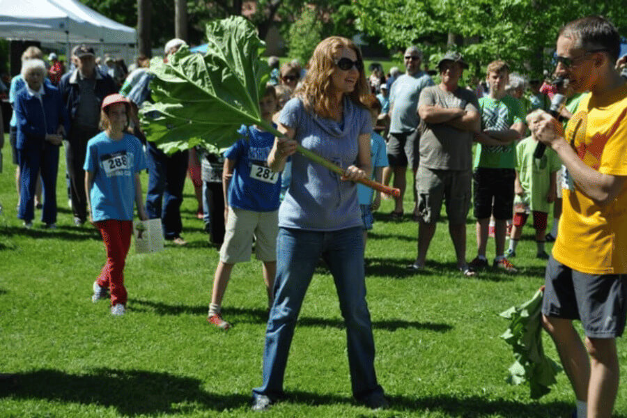 Woman holding a giant rhubarb stalk at the Rhubarb Festival in Lanesboro, MN