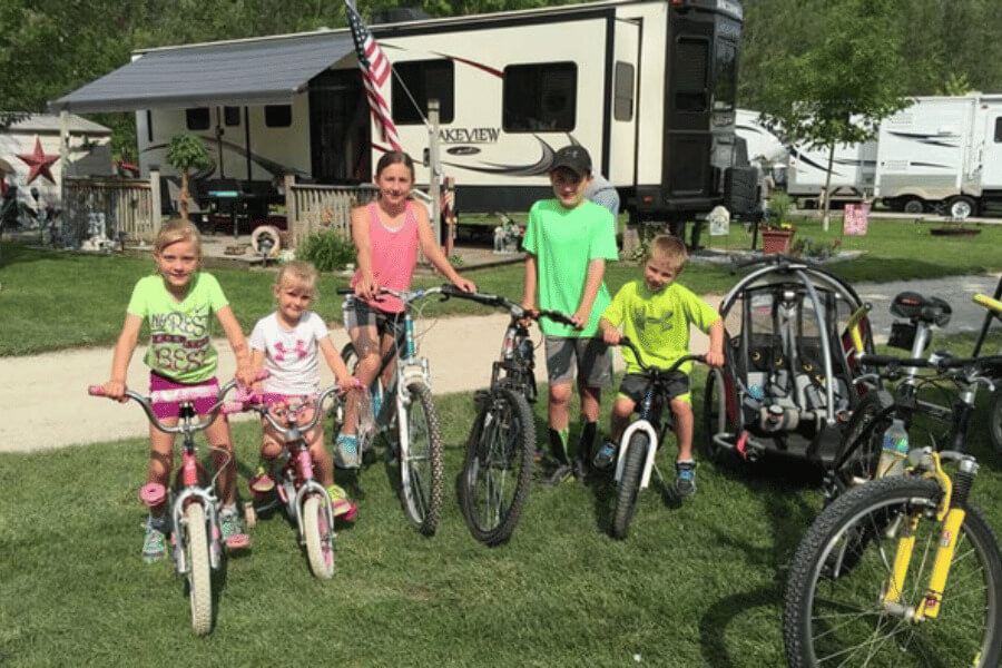 A group of kids with bicycles at Eagle Cliff Campground & Lodging near Lanesboro, Minnesota, with RVs and campground spaces in the background.
