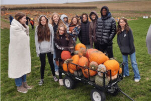 A group of people with a wagon full of pumpkins at Big Springs Farm Pumkpins and Corn Maze