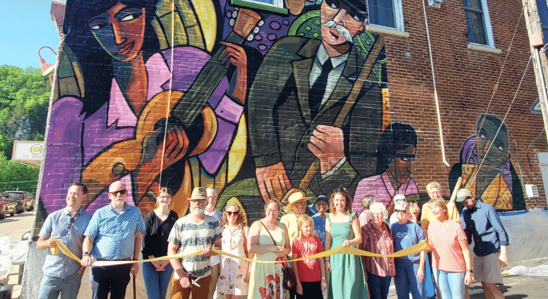 A group of people doing a ribbon cutting for a mural in Lanesboro, MN