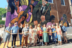 A group of people doing a ribbon cutting for a mural in Lanesboro, MN