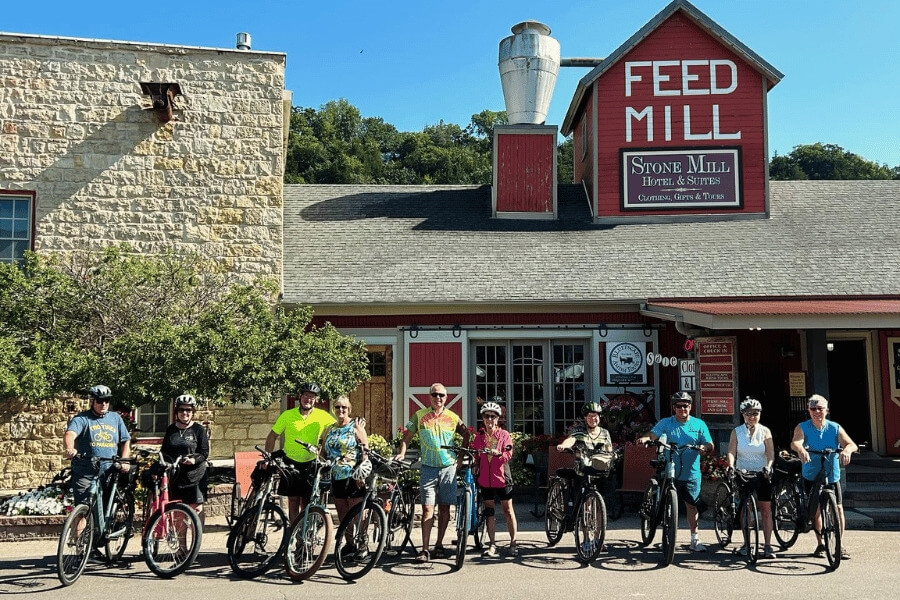 A group of bikers posing in front of Stone Mill Hotel & Suites.