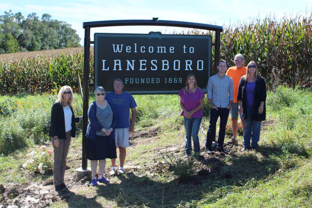 Welcome to Lanesboro sign with people standing by it