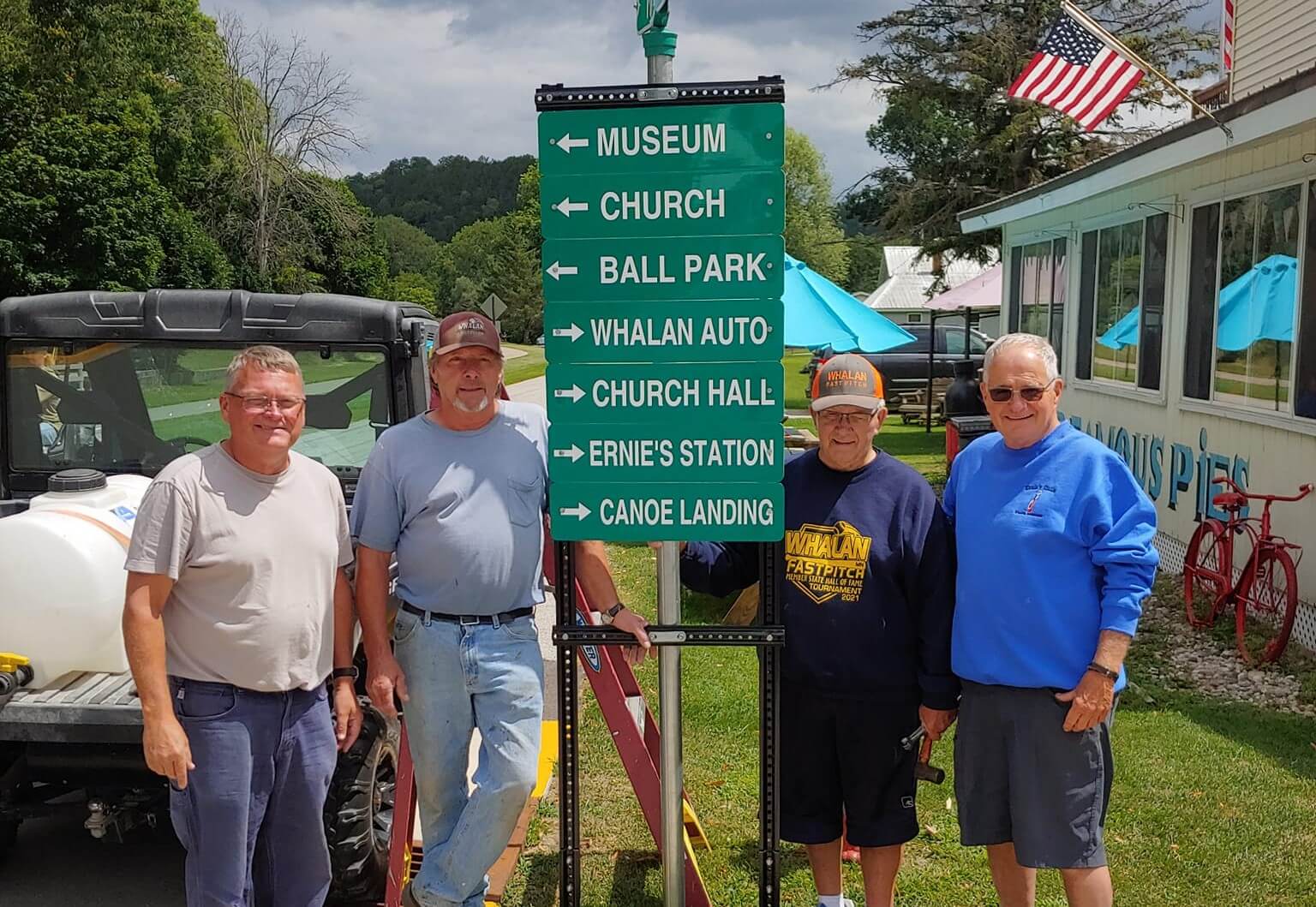 Four volunteers standing next to a new wayfinding sign they installed in Whalan, MN