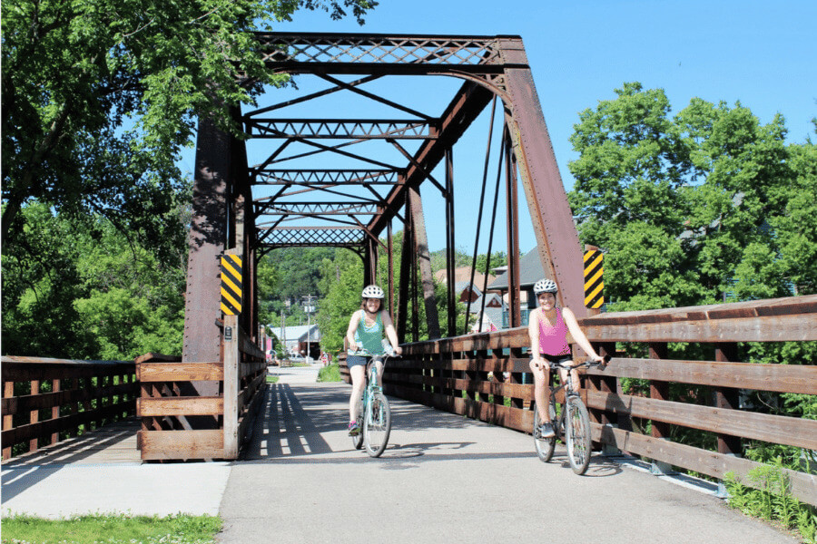 Two women riding their bikes on the Root River State Trail in Lanesboro, MN