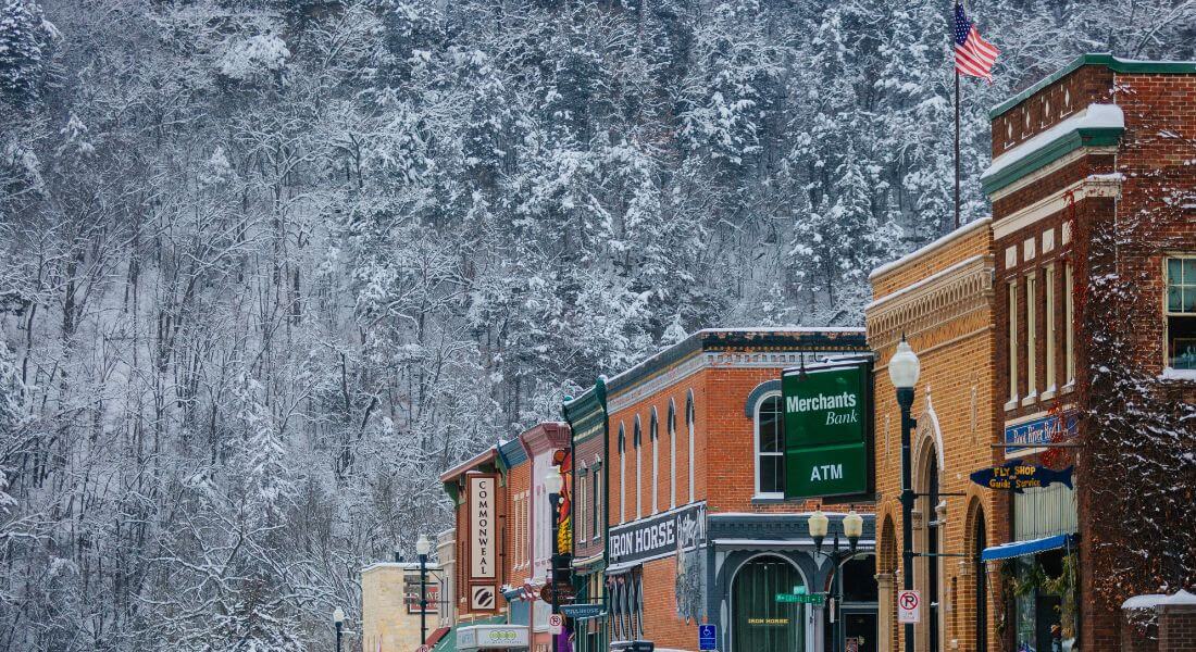 Snow-covered bluffs rise behind the historic brick storefronts of downtown Lanesboro, creating a classic small-town winter scene.