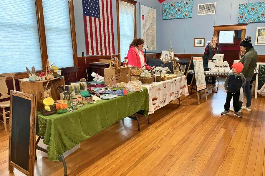 Vendors and shoppers browse handmade crafts, baked goods, and local products at the indoor Winter Market held inside the Sons of Norway Hall in Lanesboro.