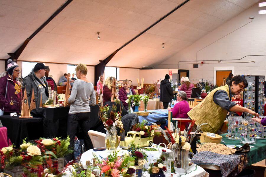 Vendors and shoppers browse handmade crafts, baked goods, and local products at the indoor Winter Market held in Lanesboro