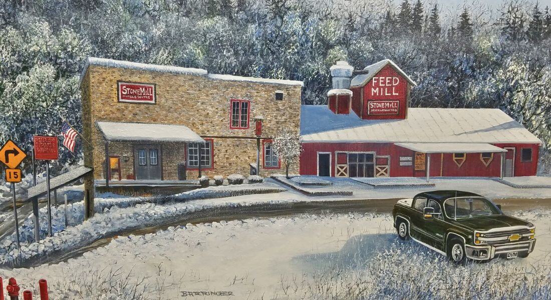 Winter painting of Stone Mill Hotel & Suites and the historic Feed Mill building in Lanesboro, Minnesota, surrounded by snow-covered trees and landscape, with a black pickup truck parked in the foreground.