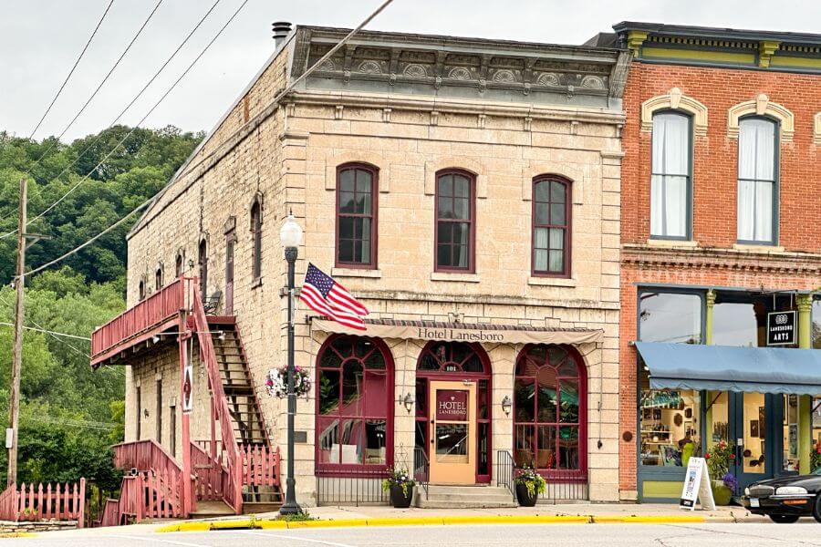 Exterior of Hotel Lanesboro in downtown Lanesboro, Minnesota, with historic stone façade, arched windows, and an American flag out front.