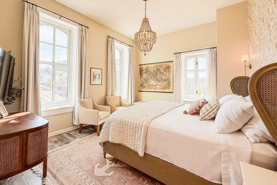 Bright renovated guest room at Hotel Lanesboro with a king bed, large windows, chandelier, and cozy seating in downtown Lanesboro, Minnesota.