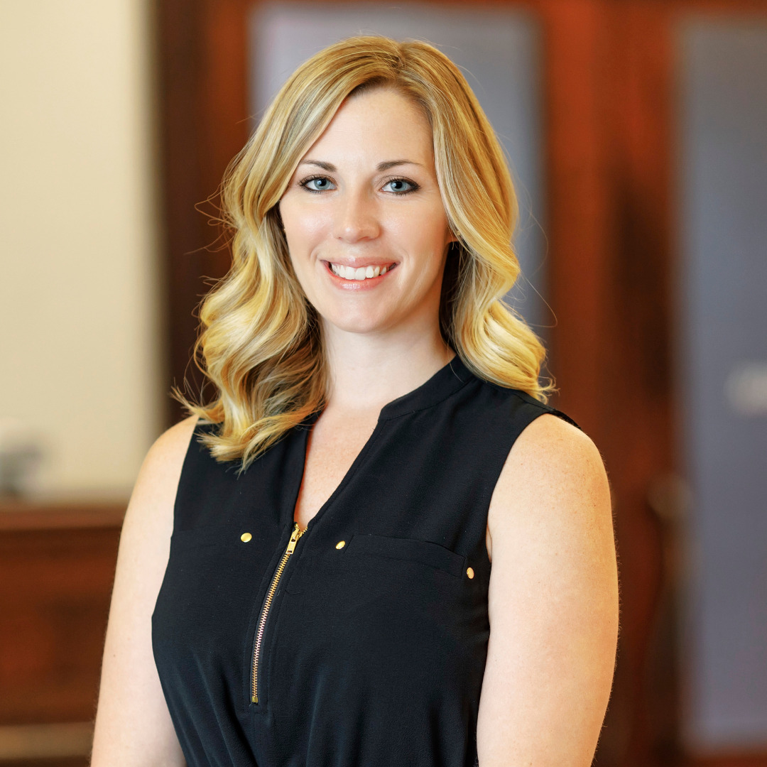 Woman smiling with black top with an office setting in the background