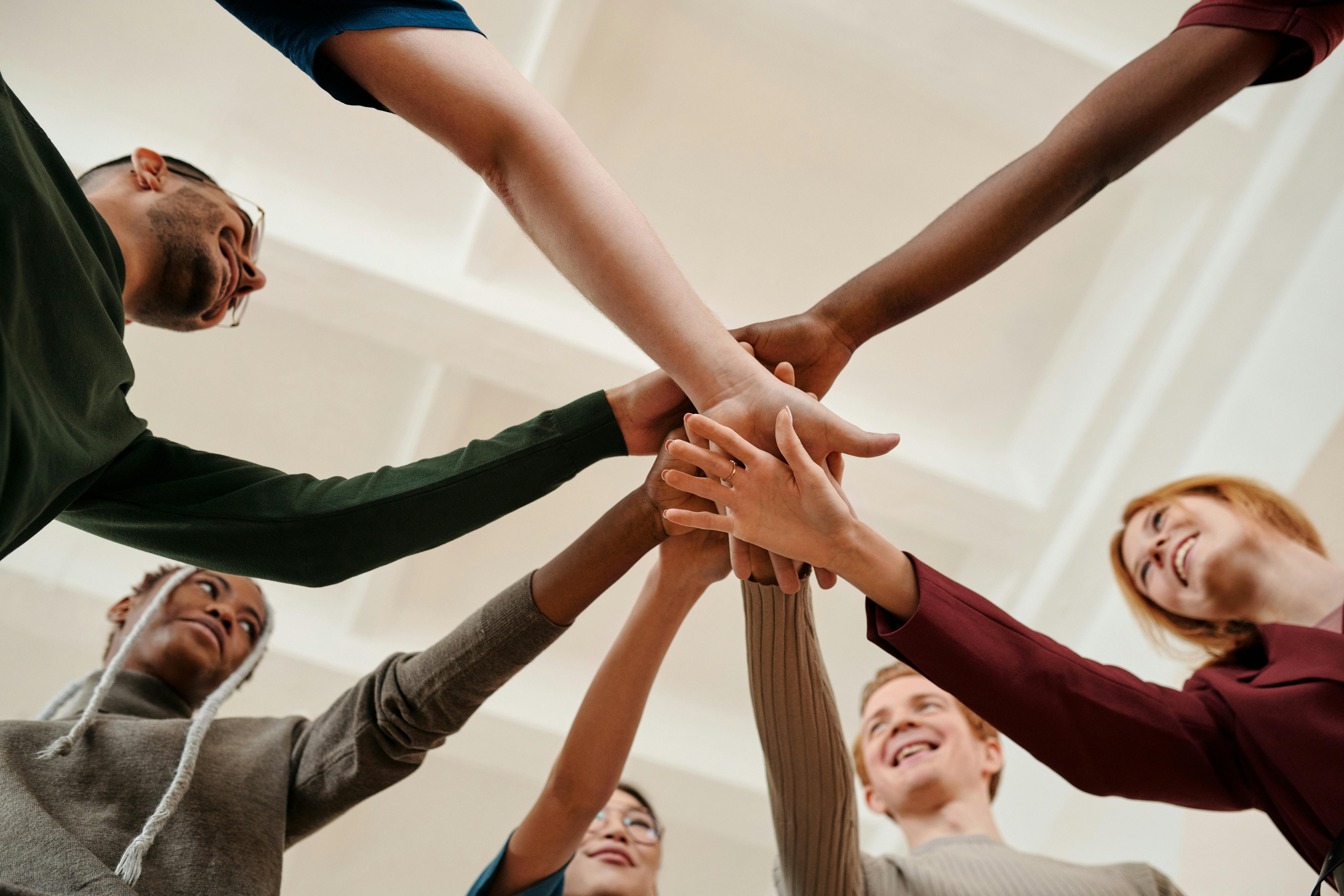 diverse group of people smiling and putting their hands together