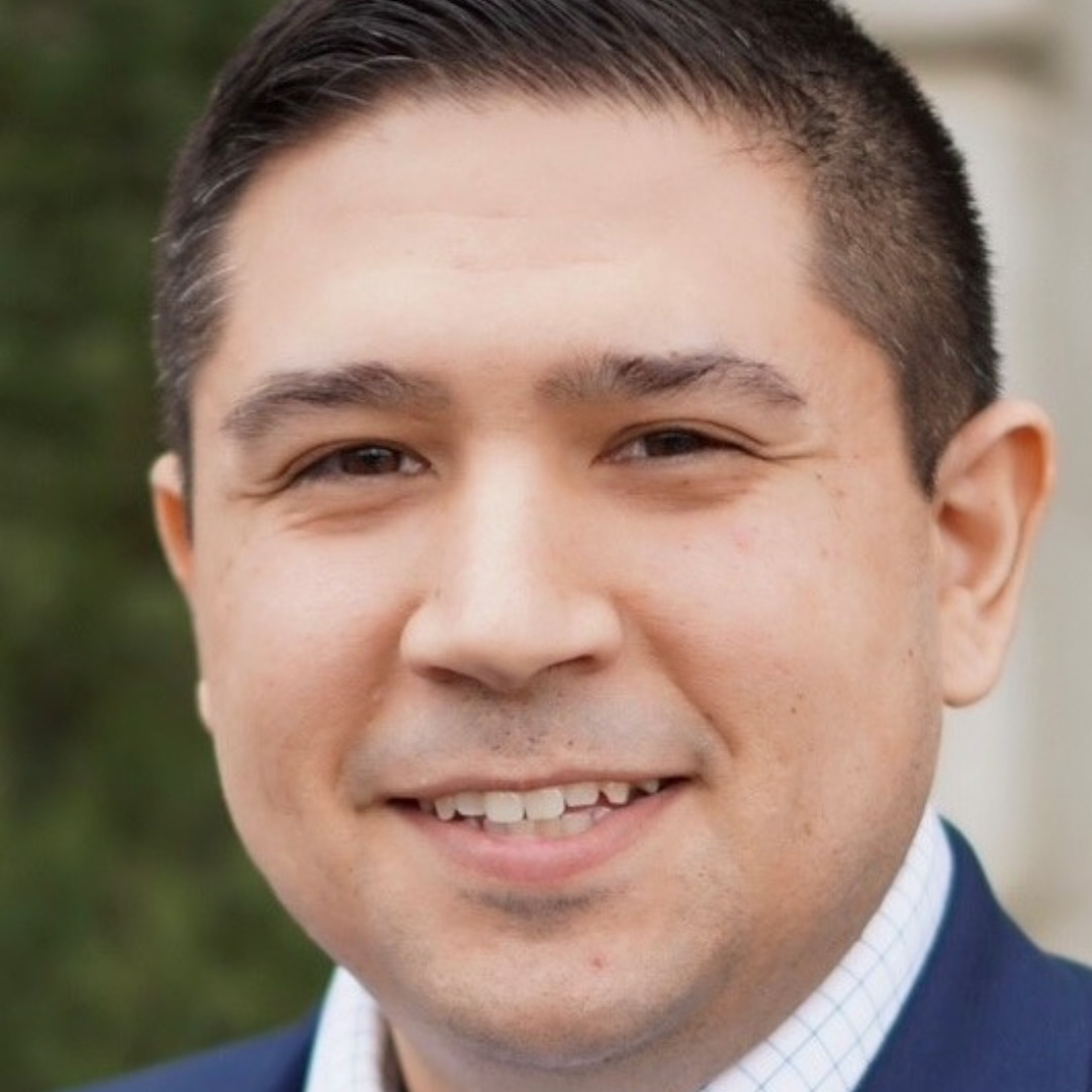 Matthew Furcean man smiling with black hair in a blue suit and white shirt