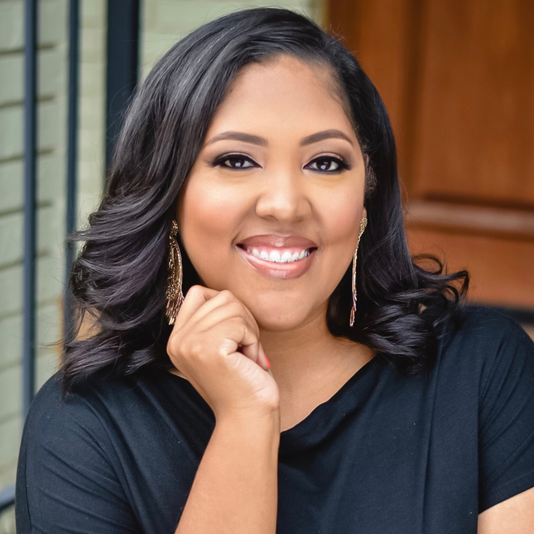 woman smiling in black shirt with her hand on her chin