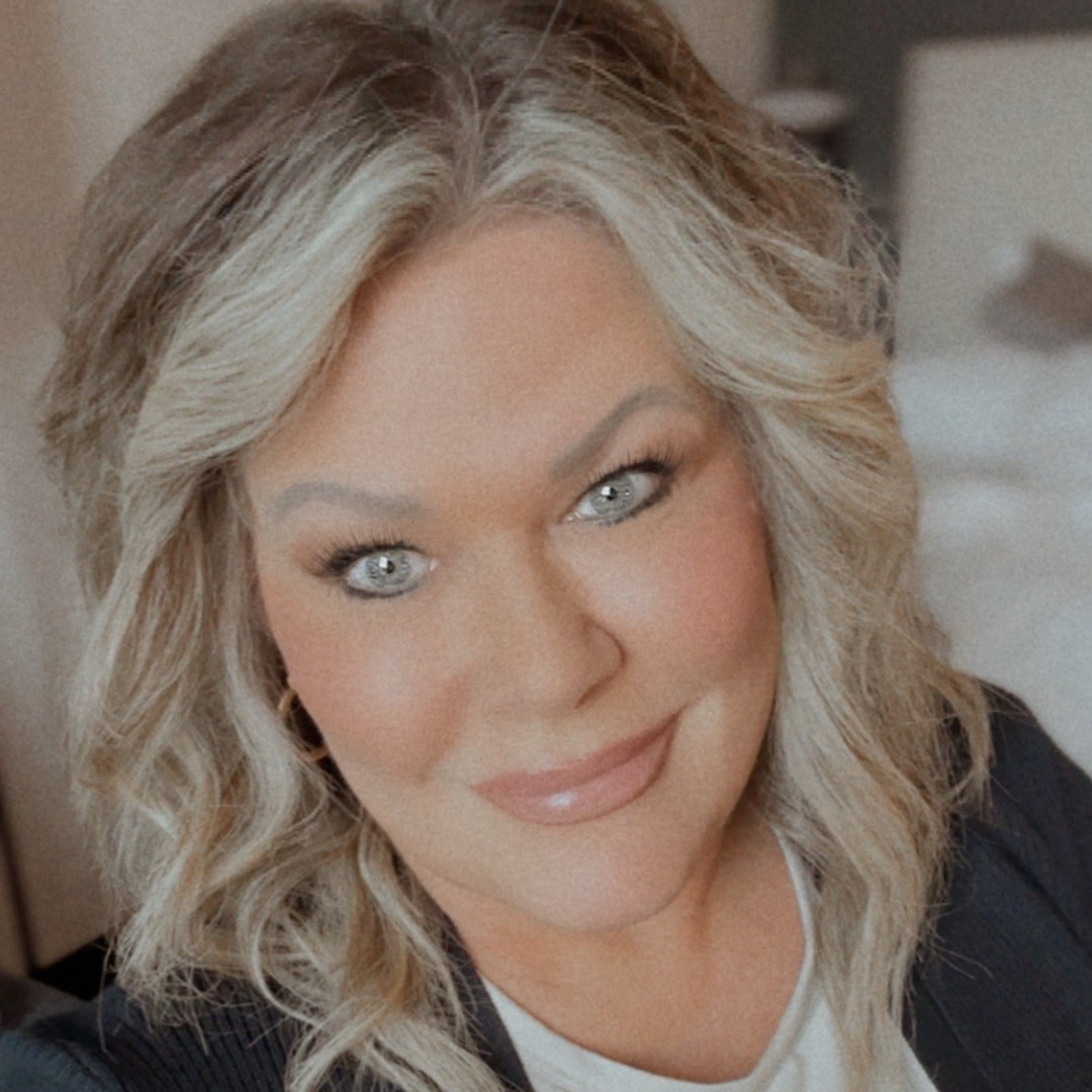 woman smiling in a black suit with blonde hair