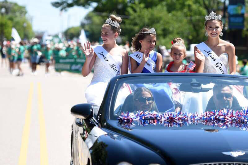 People waving from a car in a street parade