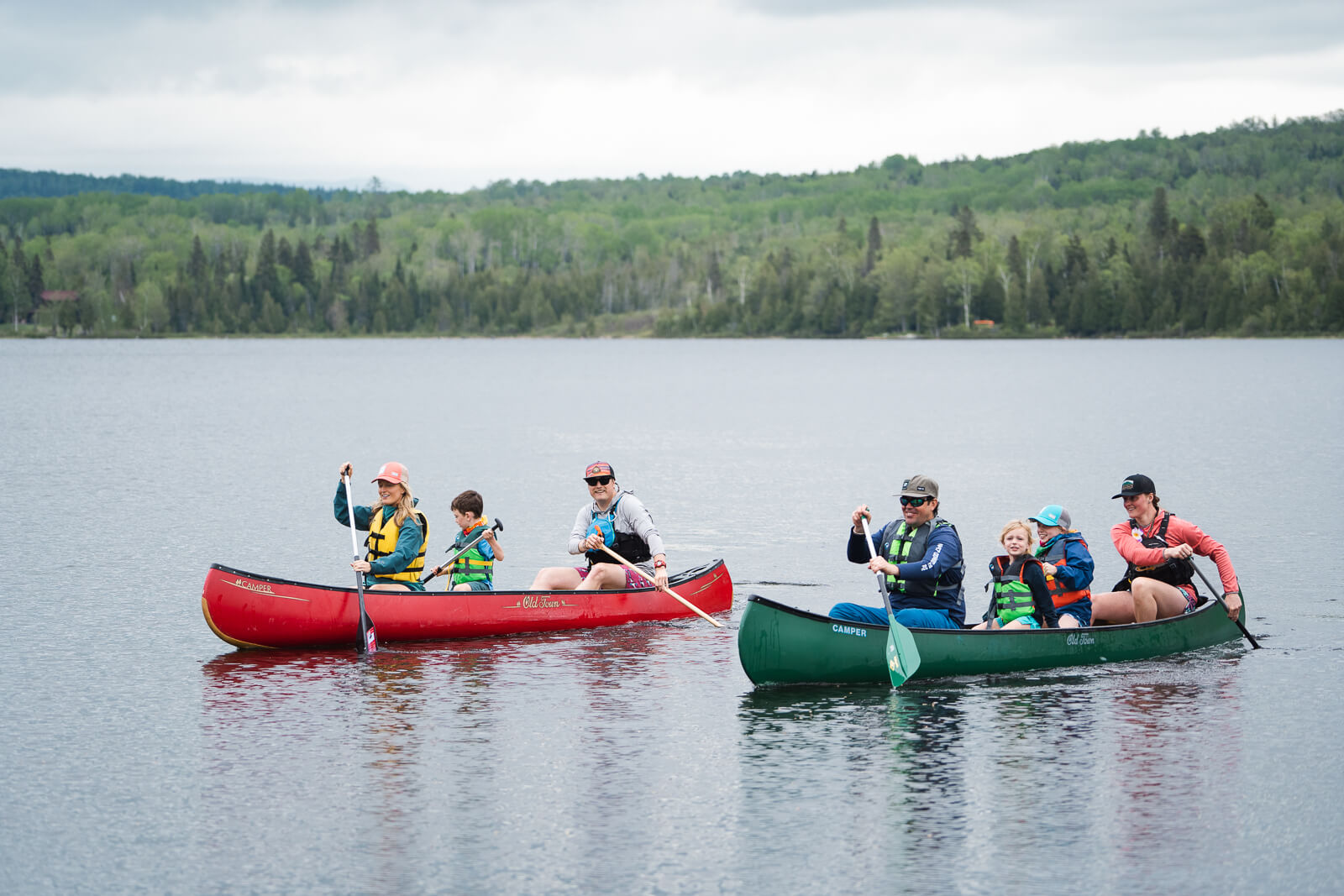 A family paddling canoes on Haley Pond in Rangeley, Maine. 