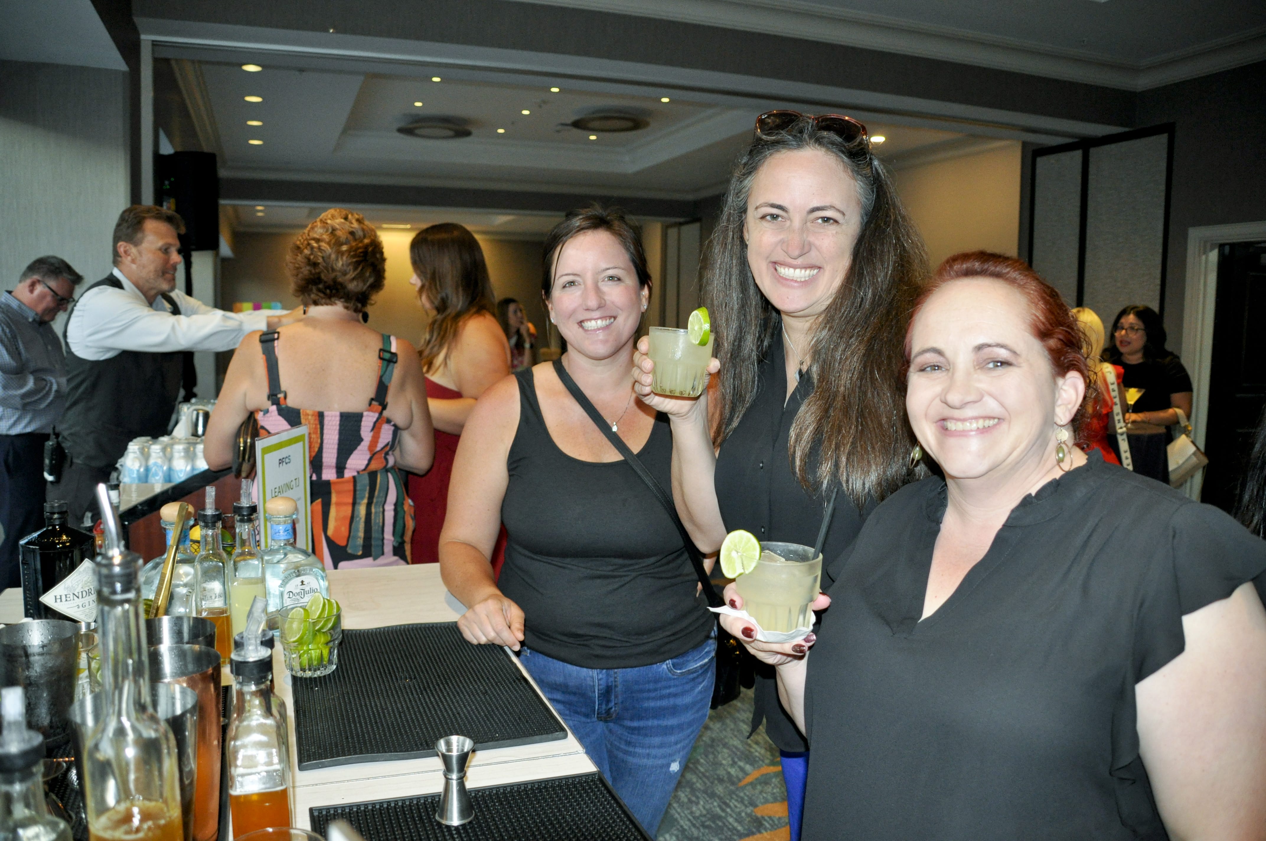 3 smiling women hold up drinks made at PowerFUEL Women's Network Mixology Event