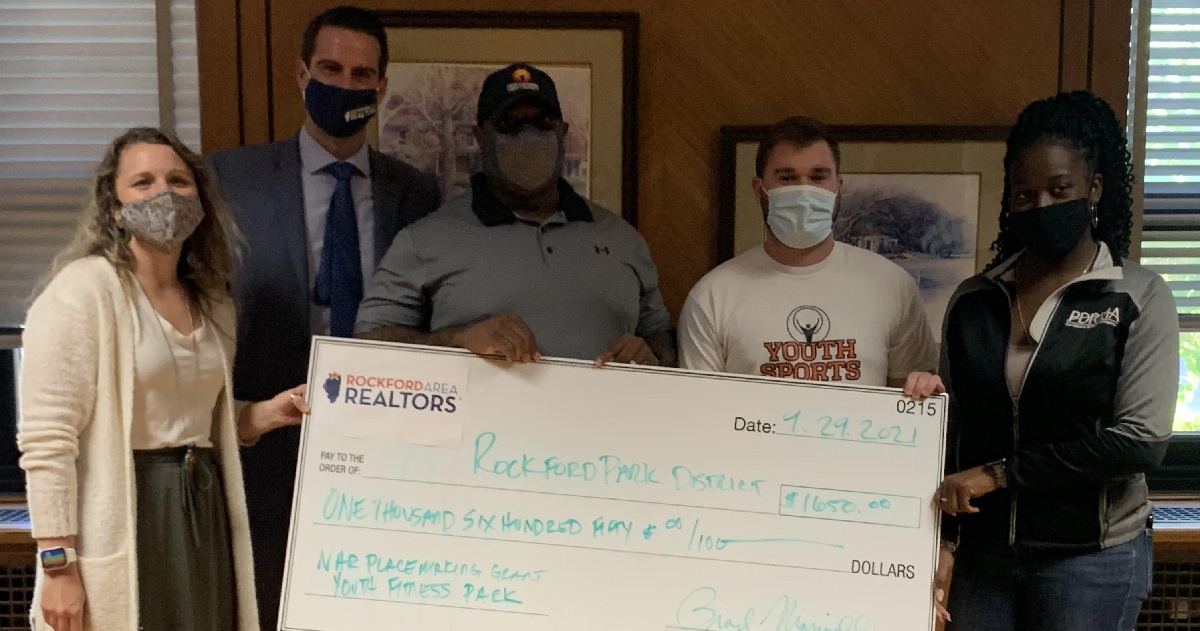 five adults standing behind large check