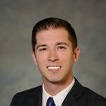 middle age man. dark hair. black suit with tie