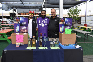 3 men behind a table selling goods