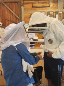Chelsea Walker, Watershed Program Manager, Westmoreland Conservation District, LW'20, assists a student with his beekeeper suit.