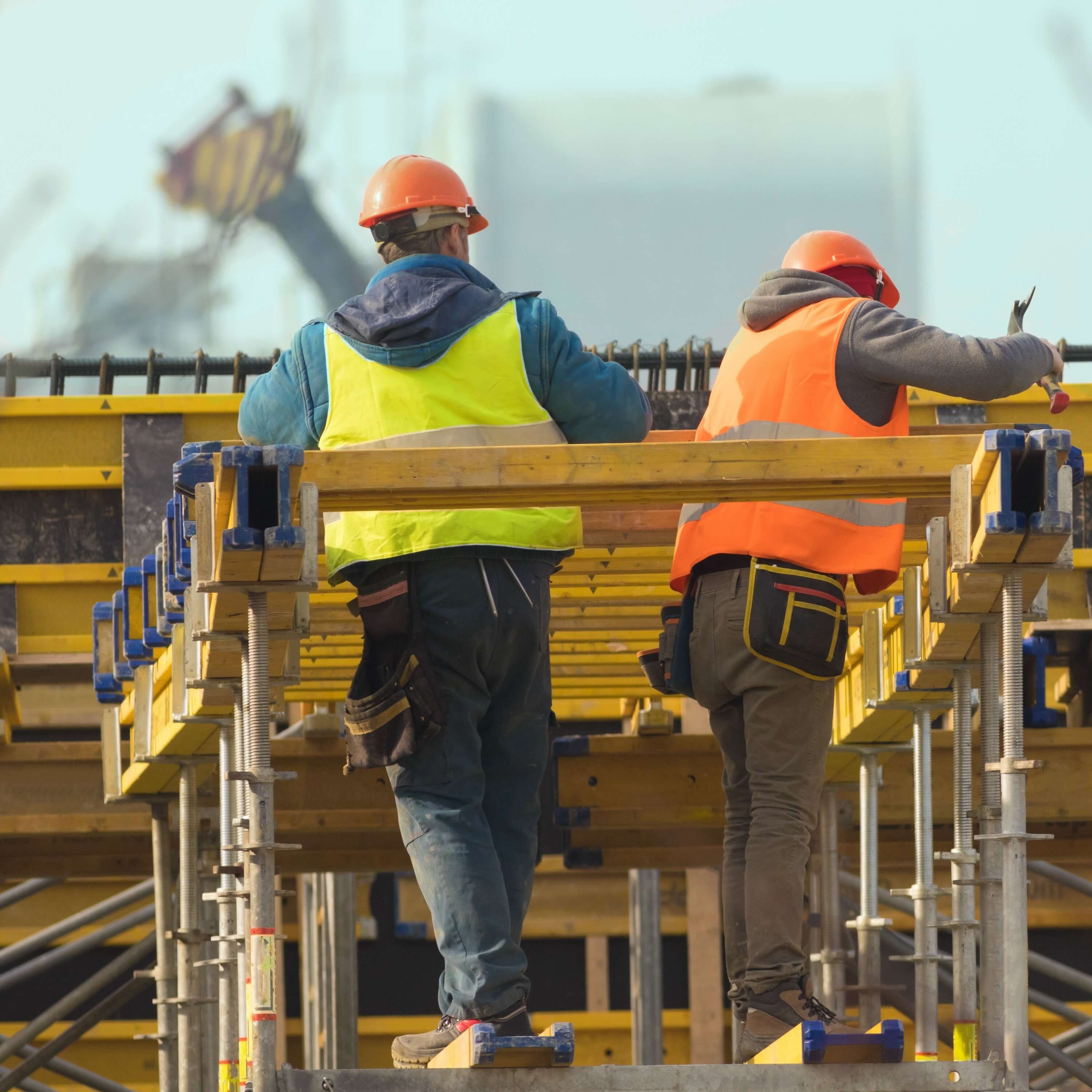 Two builders  build metal scaffolding on construction site