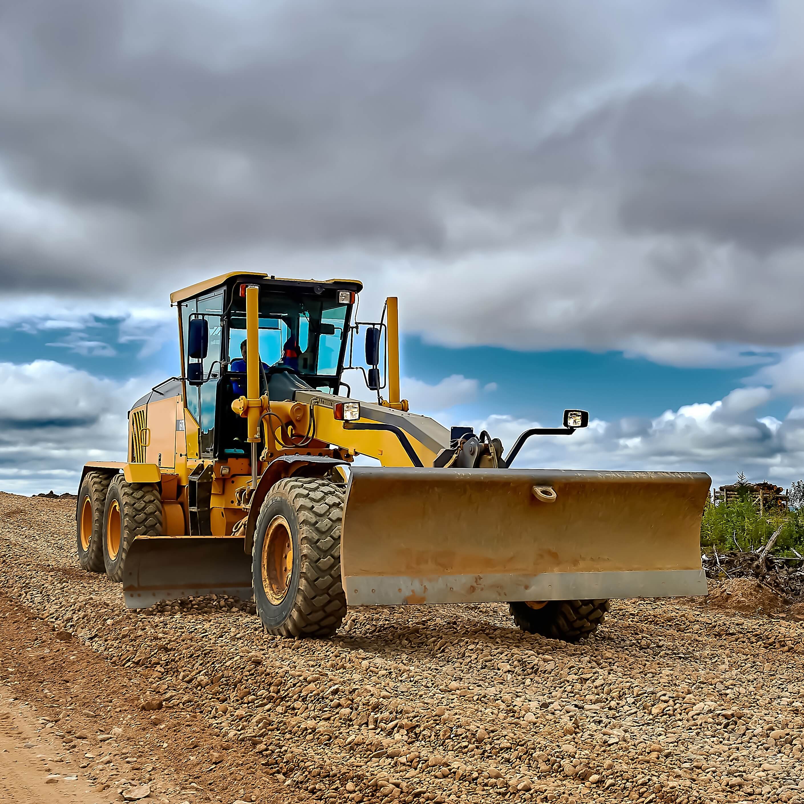 a grader on the construction site levels the rubble