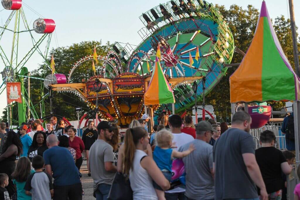 A crowd in front of rides at the Monroe County Fair