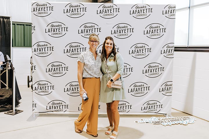 2 attendees standing in front of a Greater Lafayette Commerce backdrop.