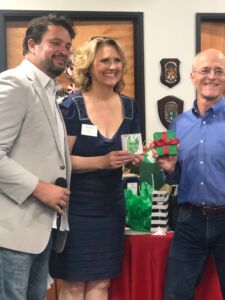 three people posing for a photo at a holiday mixer giving gifts