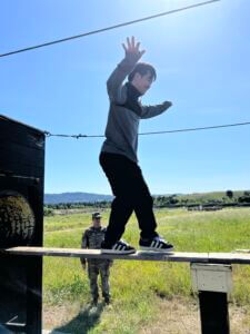 Person balancing on a bard above ground during an obstacle course exercise.