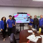 Lead cohort posed in front of a PowerPoint presentation for negotiation tactics with their teacher.