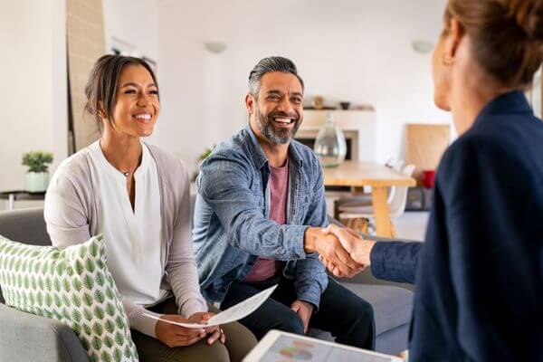 Man and woman working with a realtor. Man is shaking hands with the realtor.