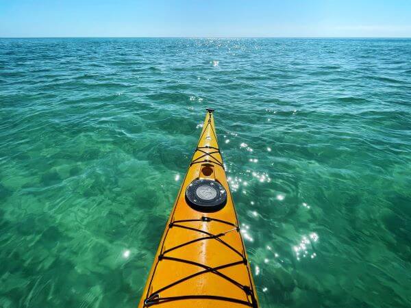 Photo of a yellow kayak floating on the bright blue water.