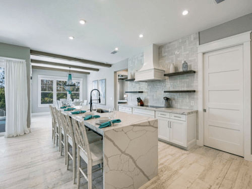 Photo of a kitchen with a large island in the center with a row of bar stools.