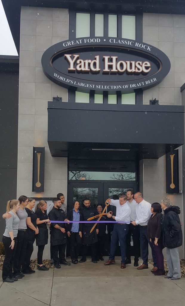 Yard House Willow Grove manager cuts the ribbon at their grand opening using the giant EMCCC scissors.