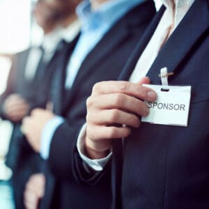 "SPONSOR" name tag worn by businessperson at event.