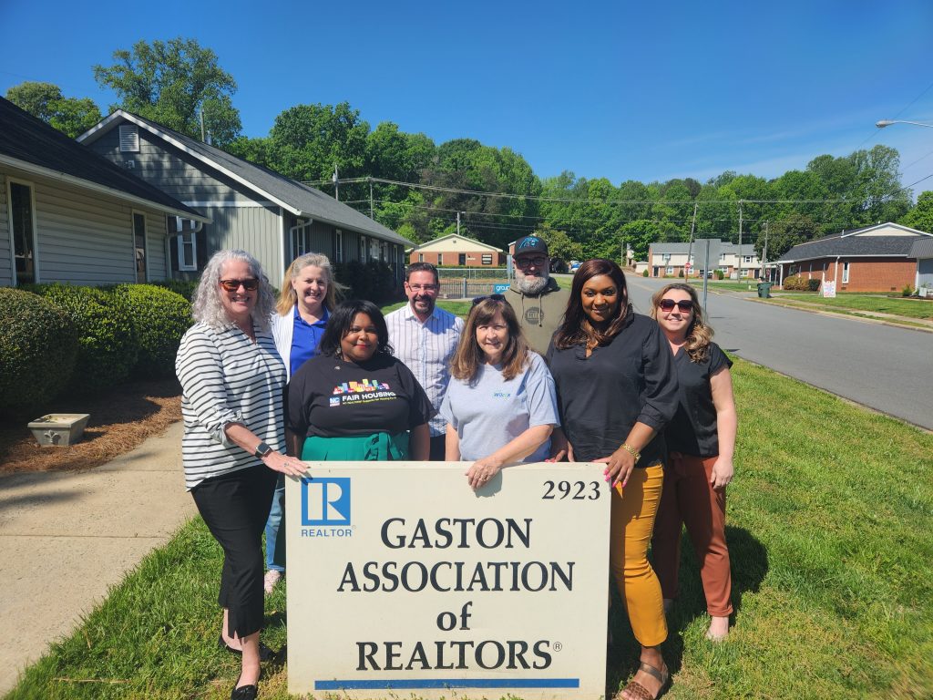 standing in front of gaston association of raltors sign